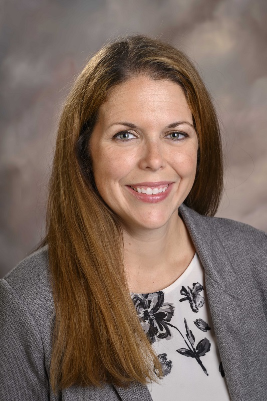 haley wears a grey blazer and has long reddish brown hair