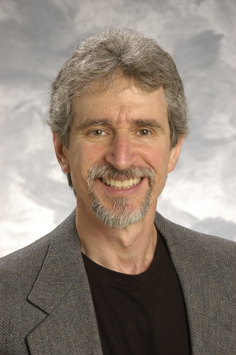 david has grey hair and goatee and wears a black shirt with a suit jacket