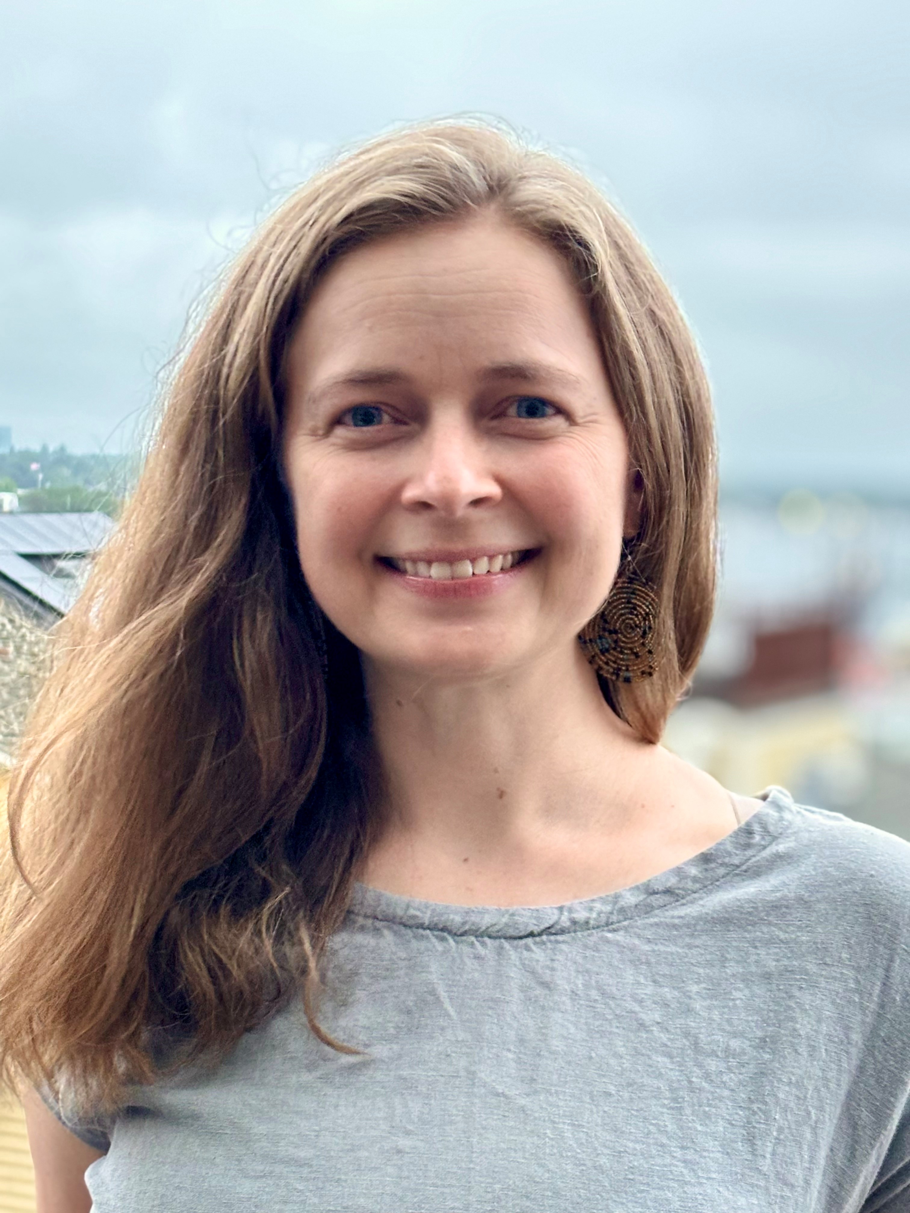 Maria Openshaw has medium length light brown hair is is wearing a grey t-shirt