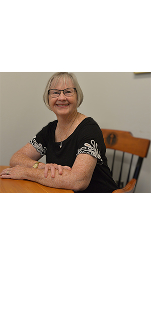woman sits at a table with a black and white top