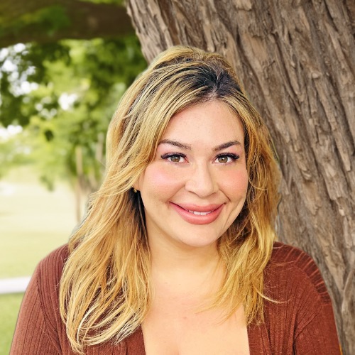 Rachel Terra Norton has medium length blonde hair and is wearing a brown shirt.