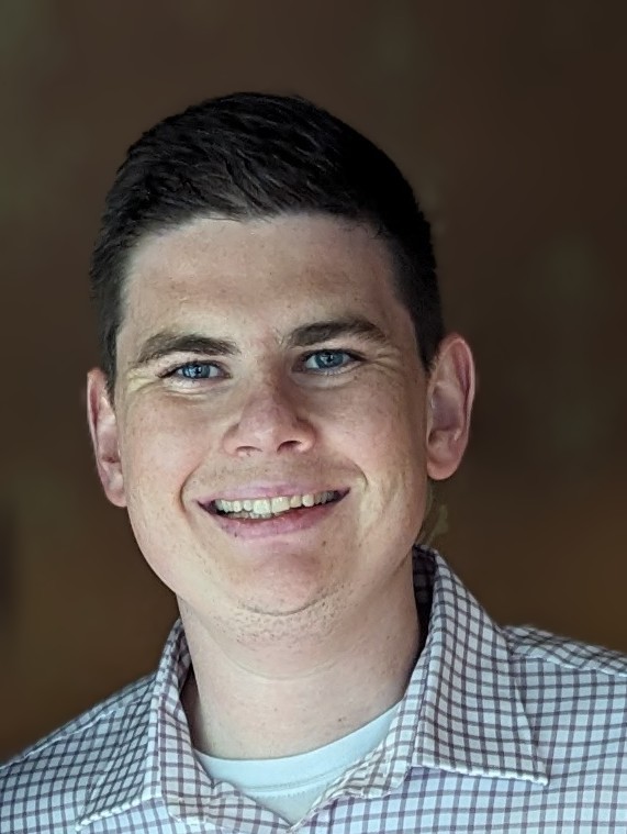 Matt O'Sullivan has short brown hair and is wearing a white and black plaid shirt