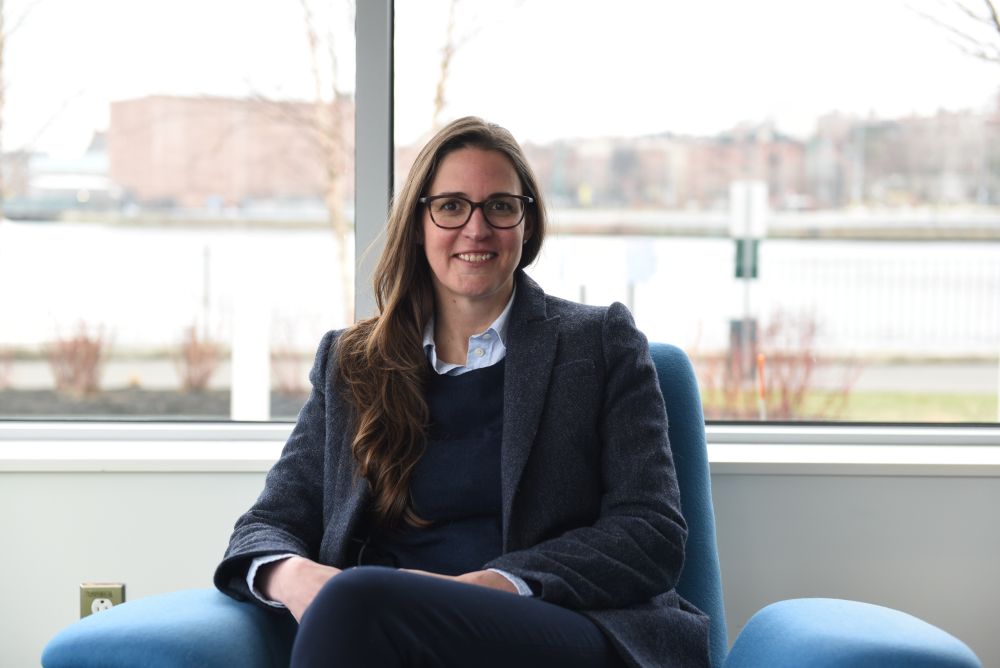 A woman sits in a chair in front of a window