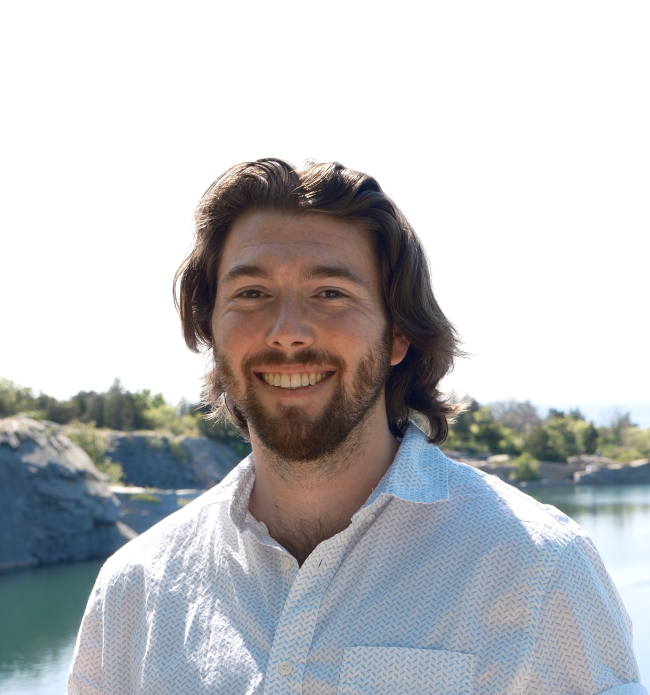 Jaryd Sullivan has shoulder length brown hair, a short beard, and is wearing a white button down.