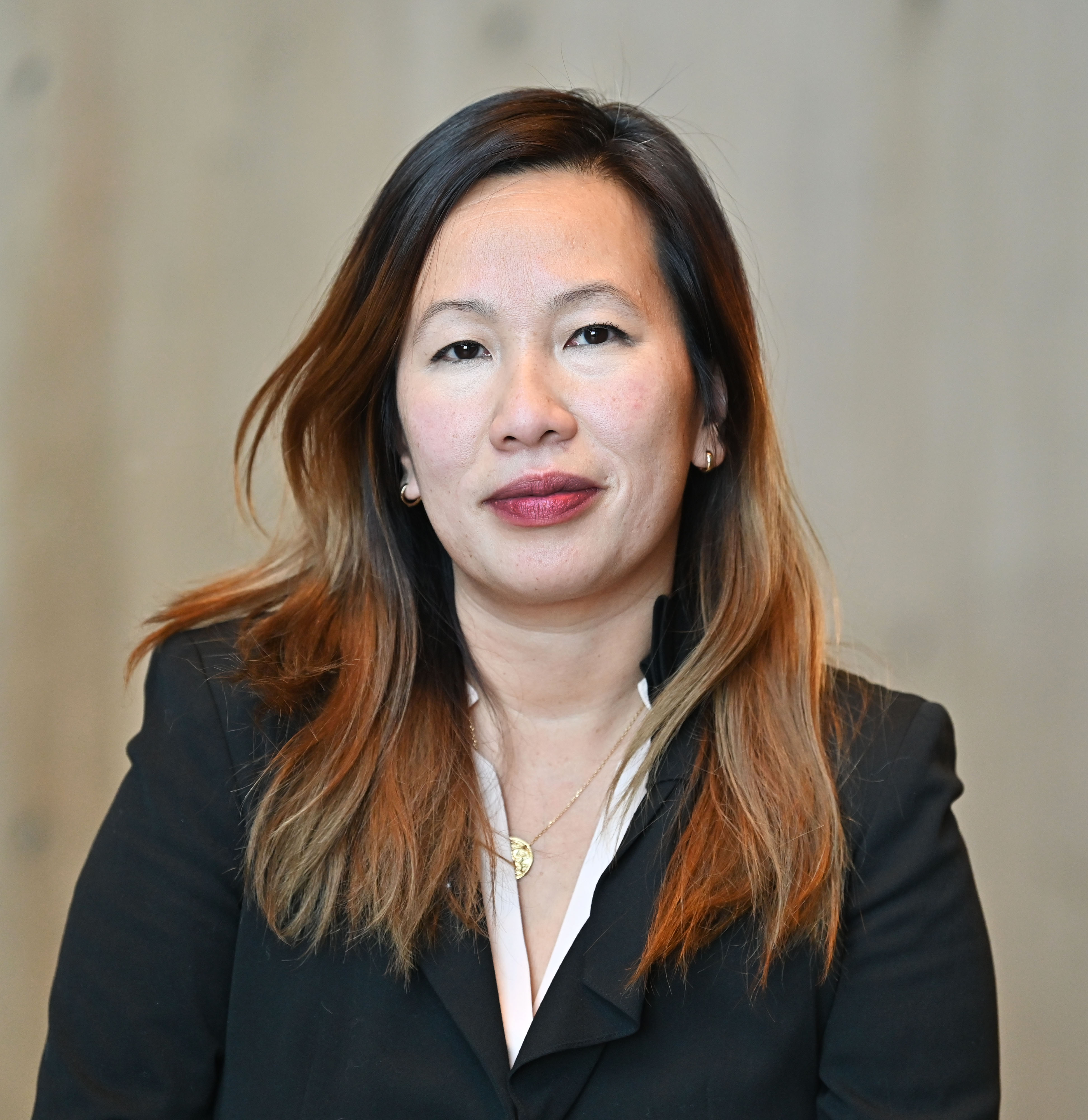 Headshot of woman with long brown hair looking at the camera and wearing a black jacket