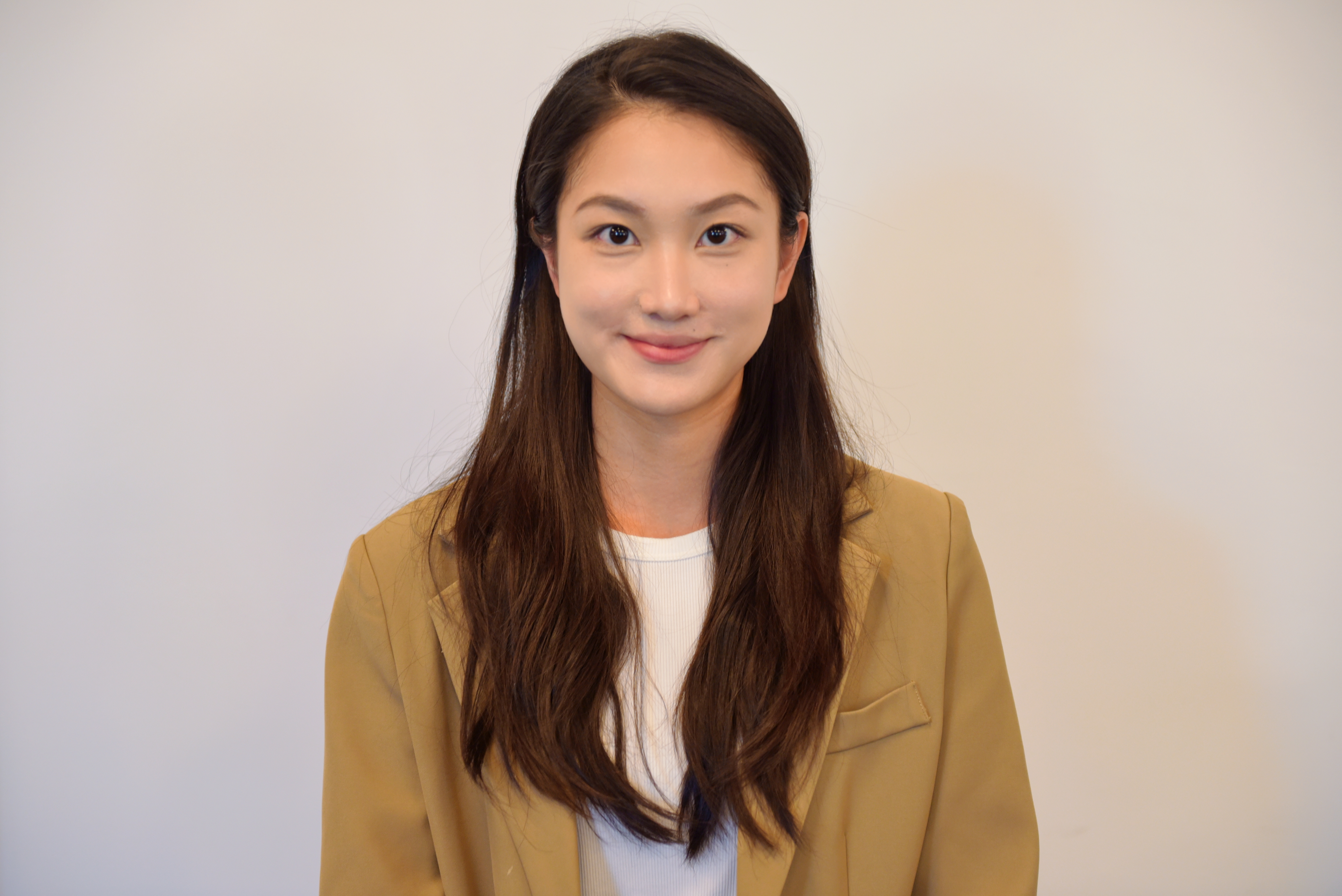 Headshot of womand with long dark hair wearing a white shirt and light brown jacket