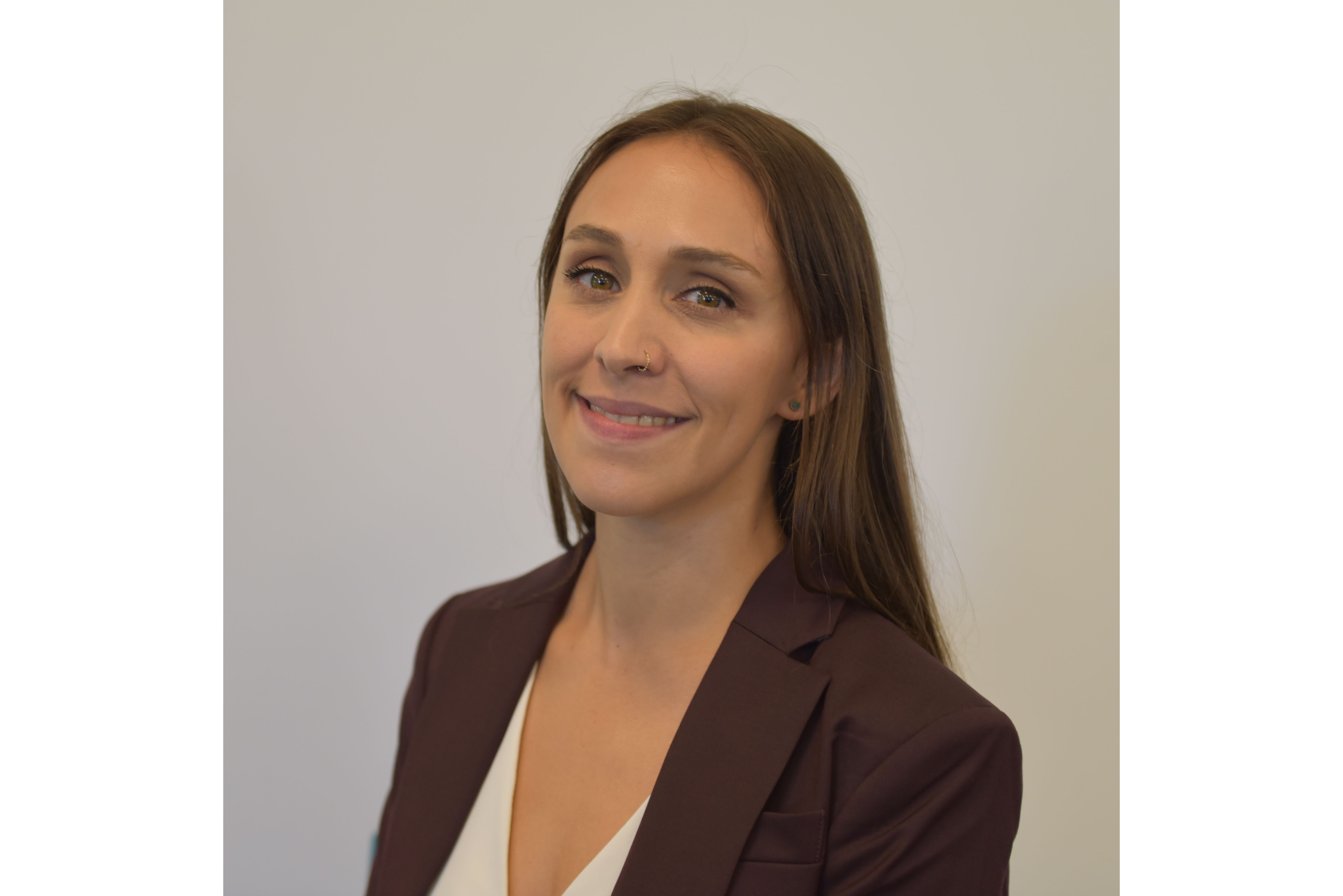 Headshot of Woman with long dark hair wearing white shirt and black jacket against a white background