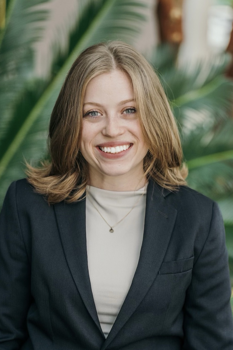 Headshot of woman with blonde hair wearing a tan shirt and black jacket