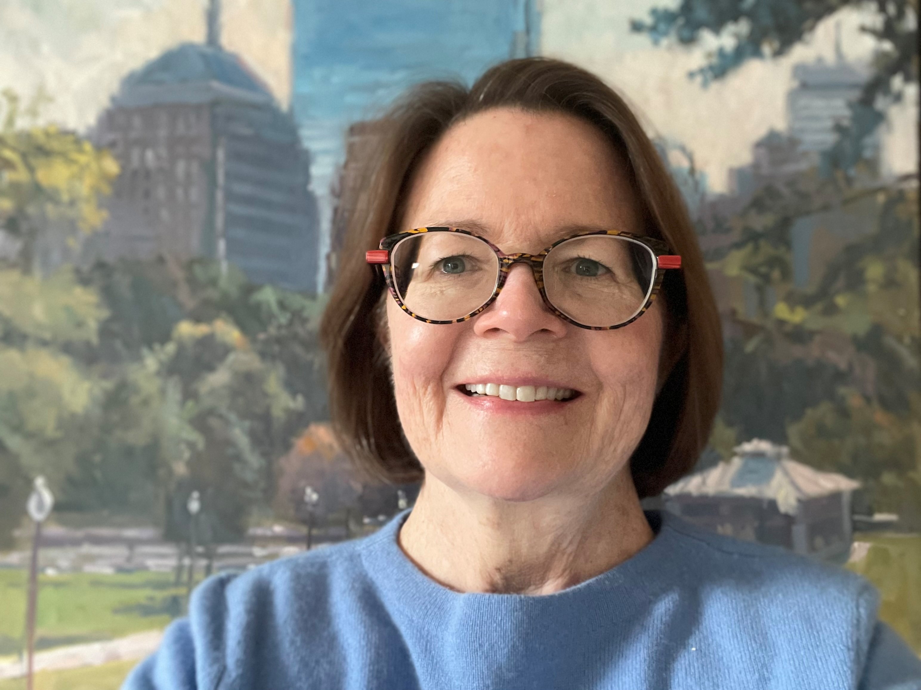Photo of woman with dark hair wearing glasses and a blue shirt