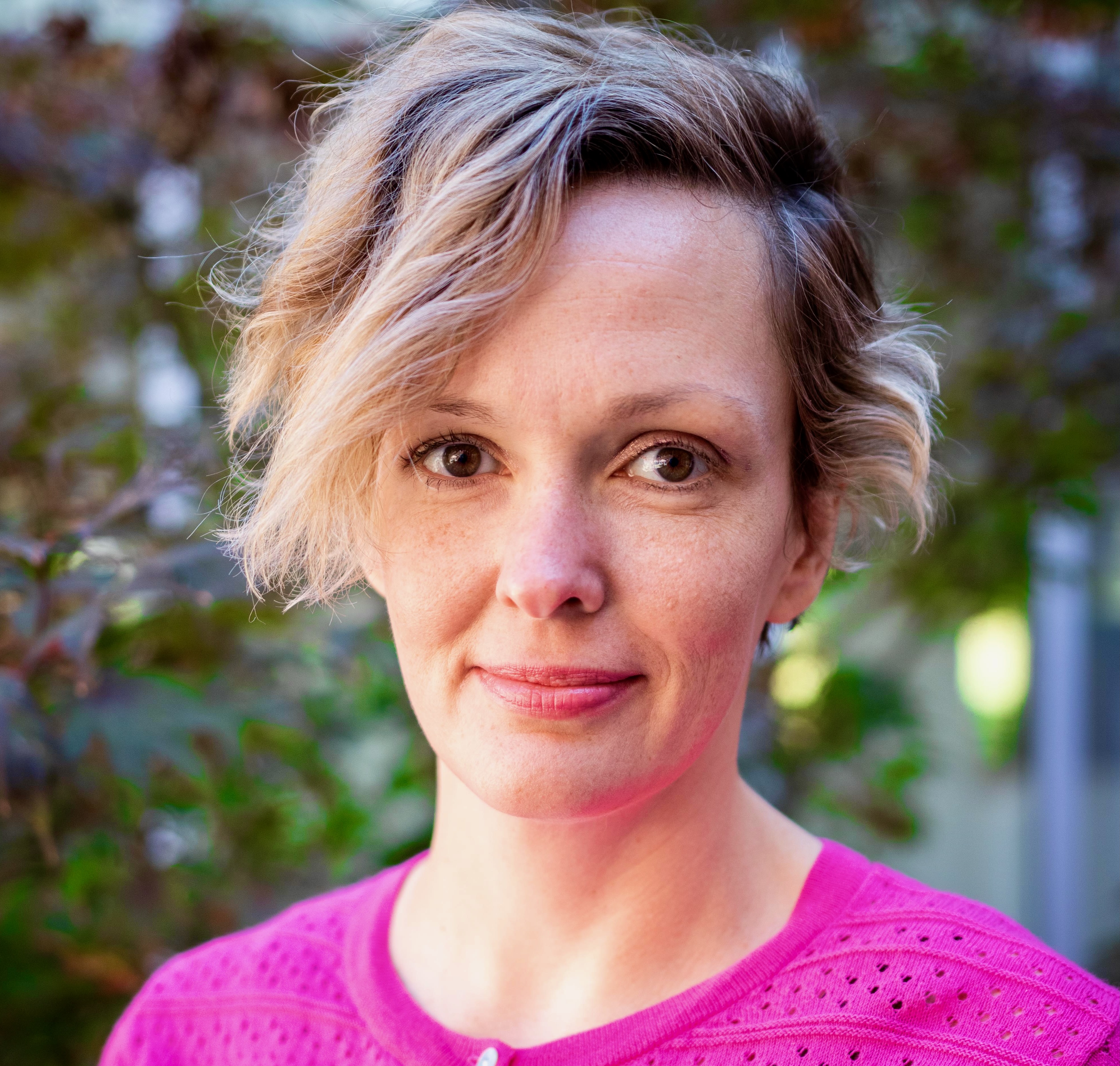 Headshot of woman with blond hair wearing pink sweater