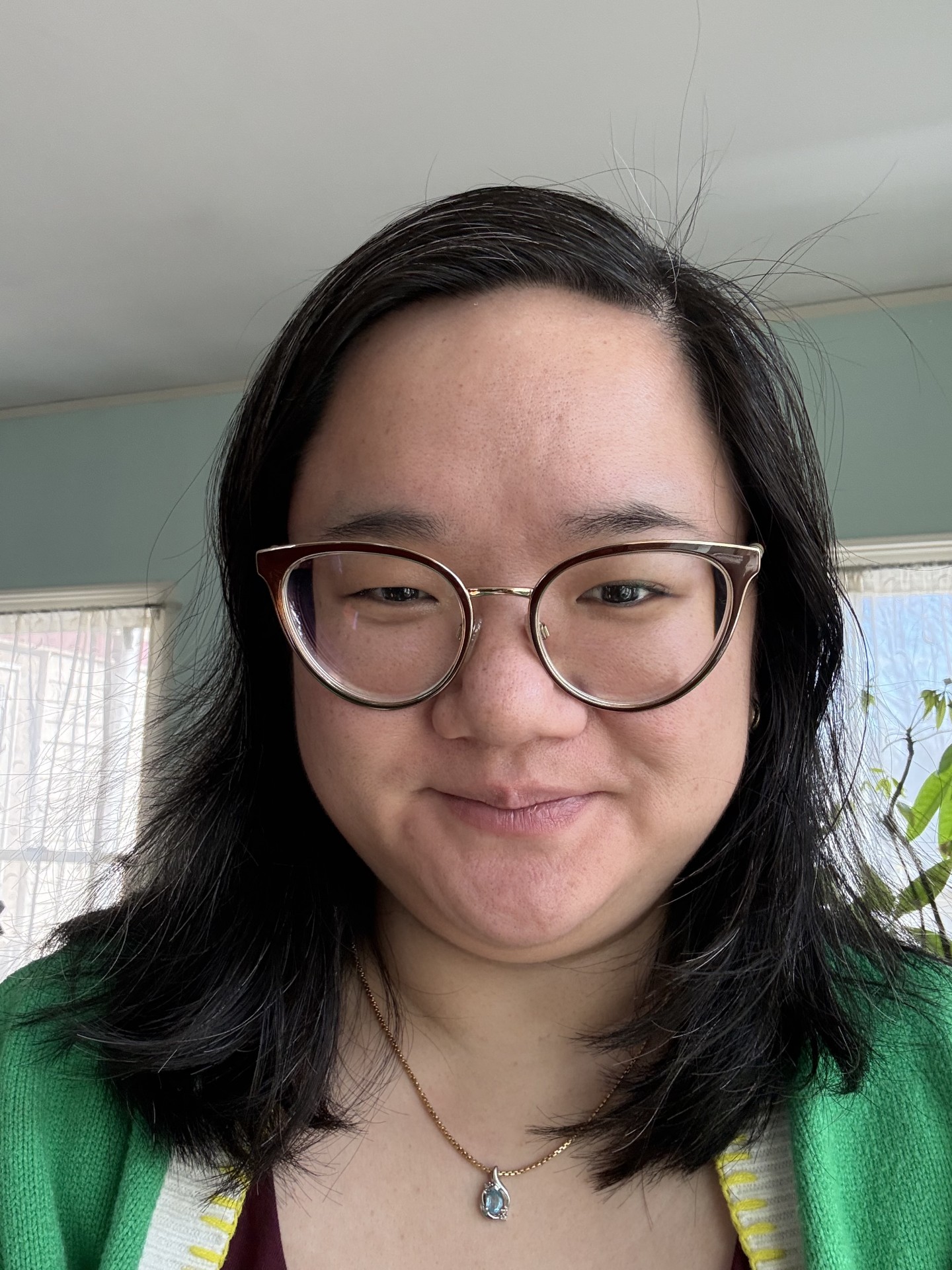 Headshot of woman with long black hair wearing glasses and a green shirt