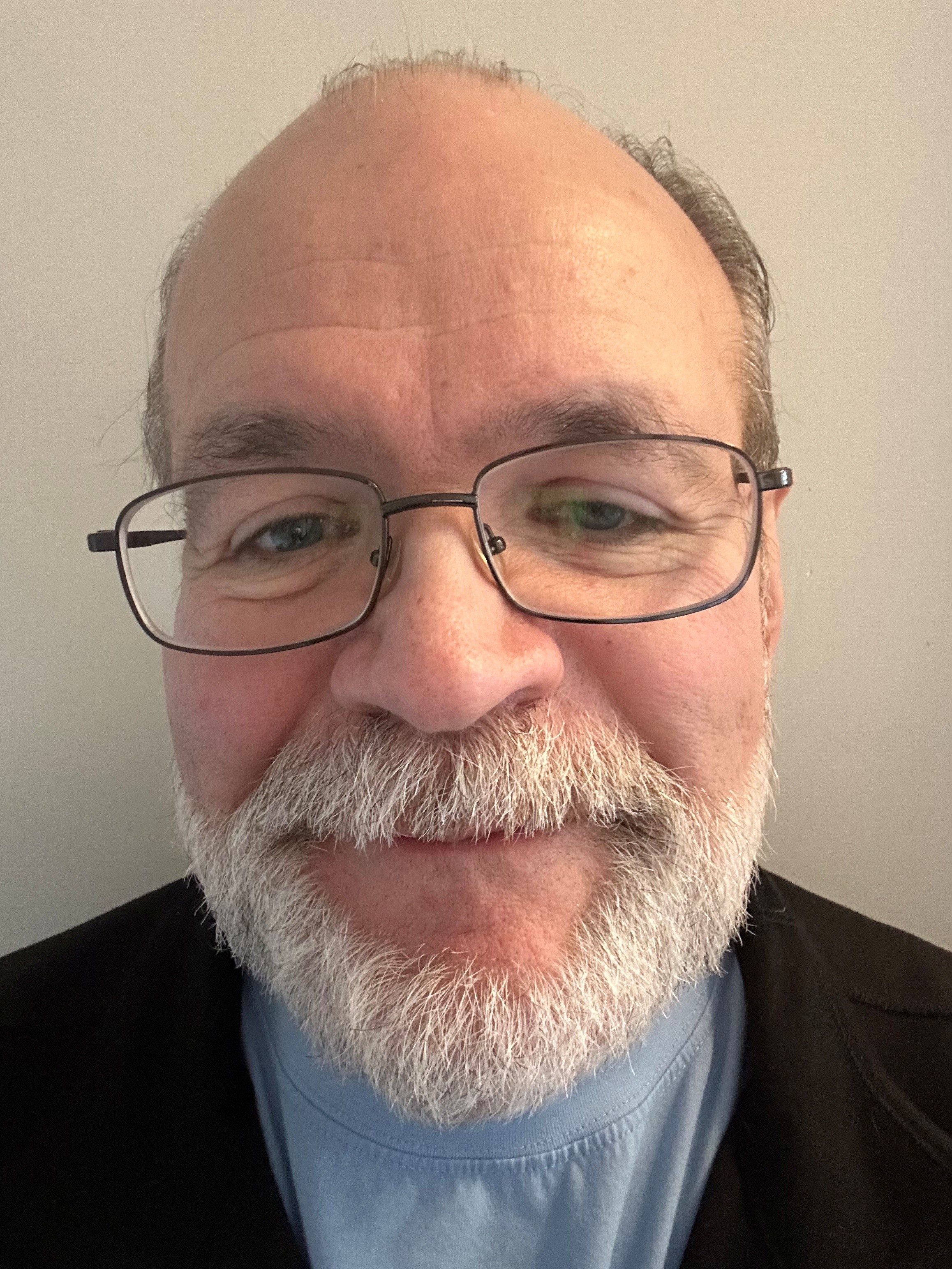 Headshot of man white white beard and mustache wearing glasses against a white background
