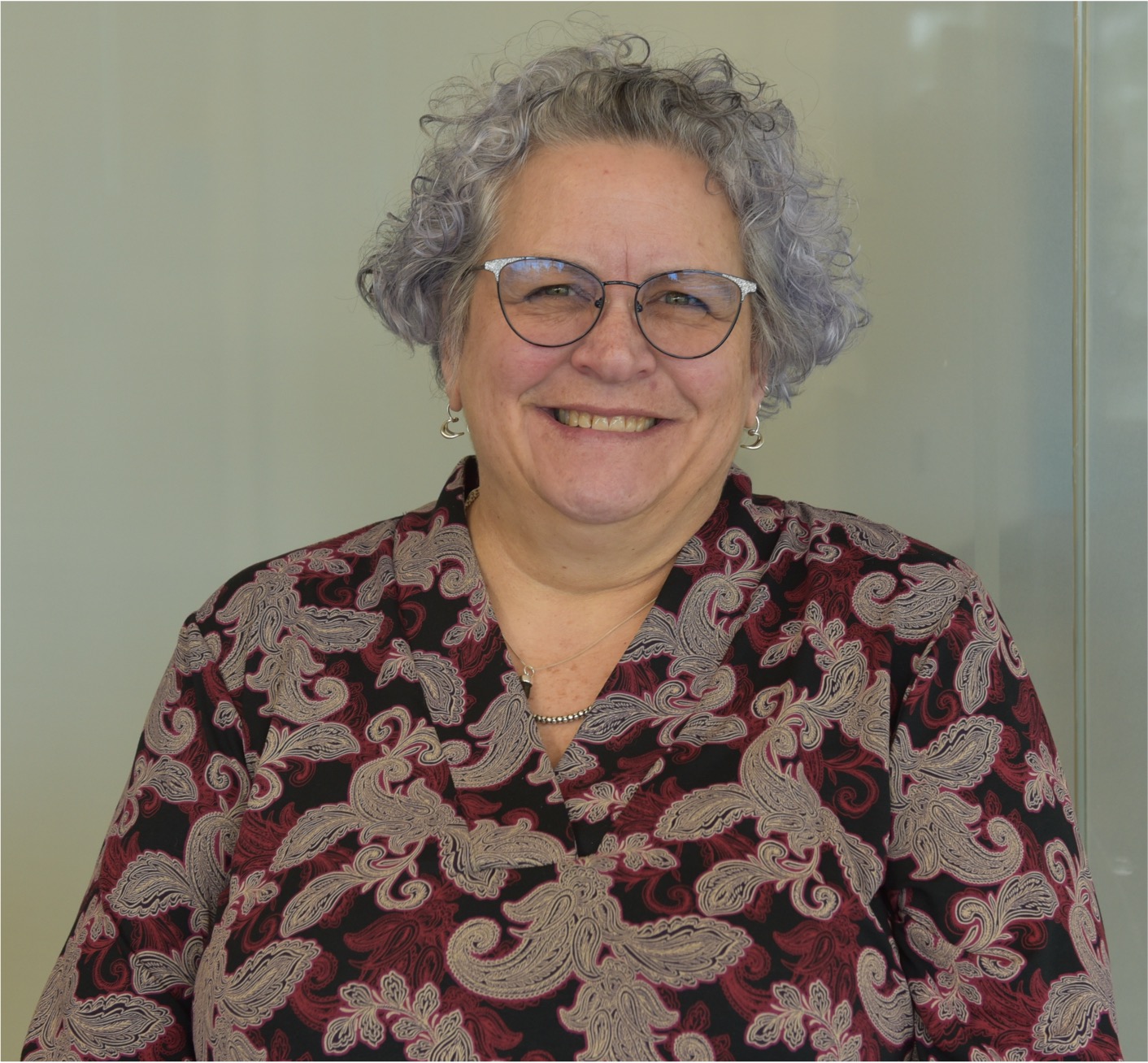 Karen has black framed glasses and grey wavy hair 