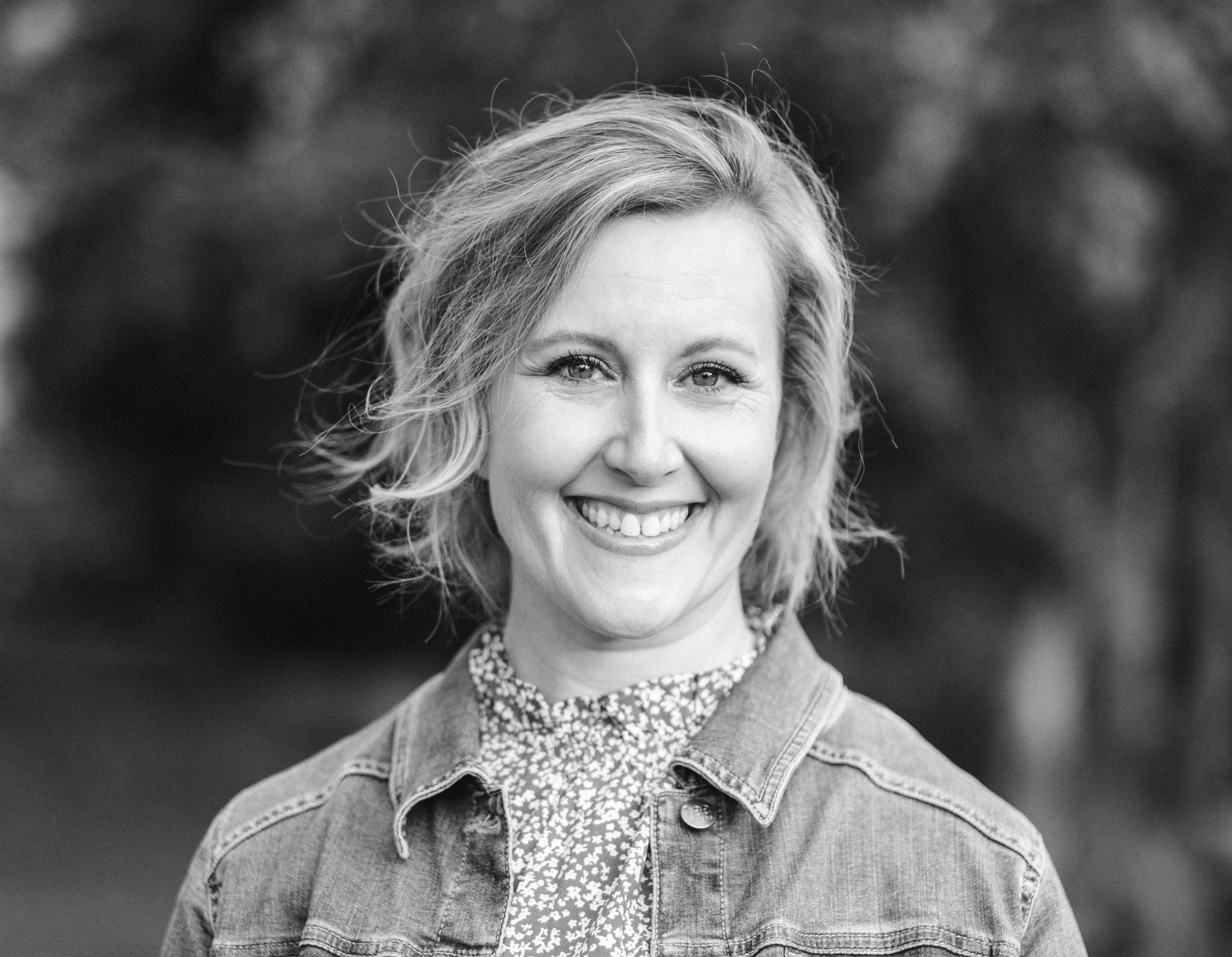 Black and white headshot of woman with shoulder length hear wearing a denim jacket