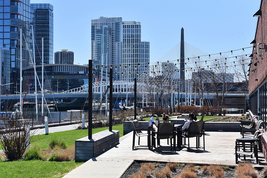 a patio in the sun with boston skyline and water in the background