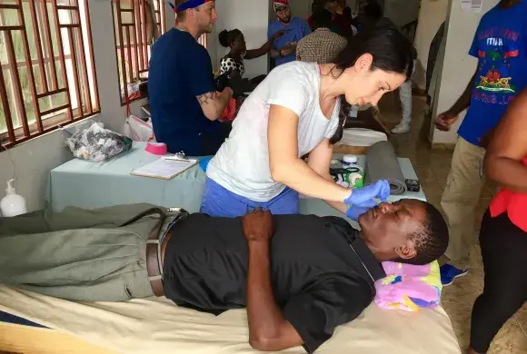 woman attends to a man's face who is lying in a hospital bed