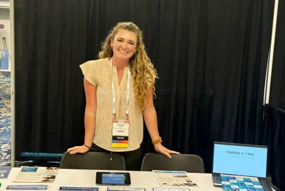 katie stands in front of a table full of papers at a conference
