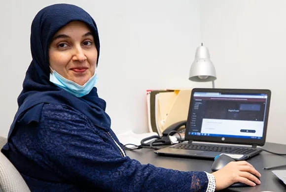 A woman sits at a desk with a laptop computer in front of her