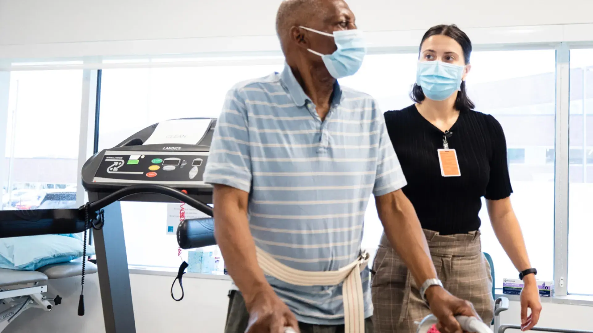 A man using a walker, working with a physical therapist 