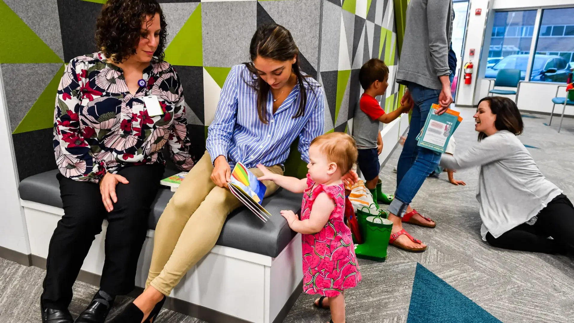 Room with adults reading and interacting with children