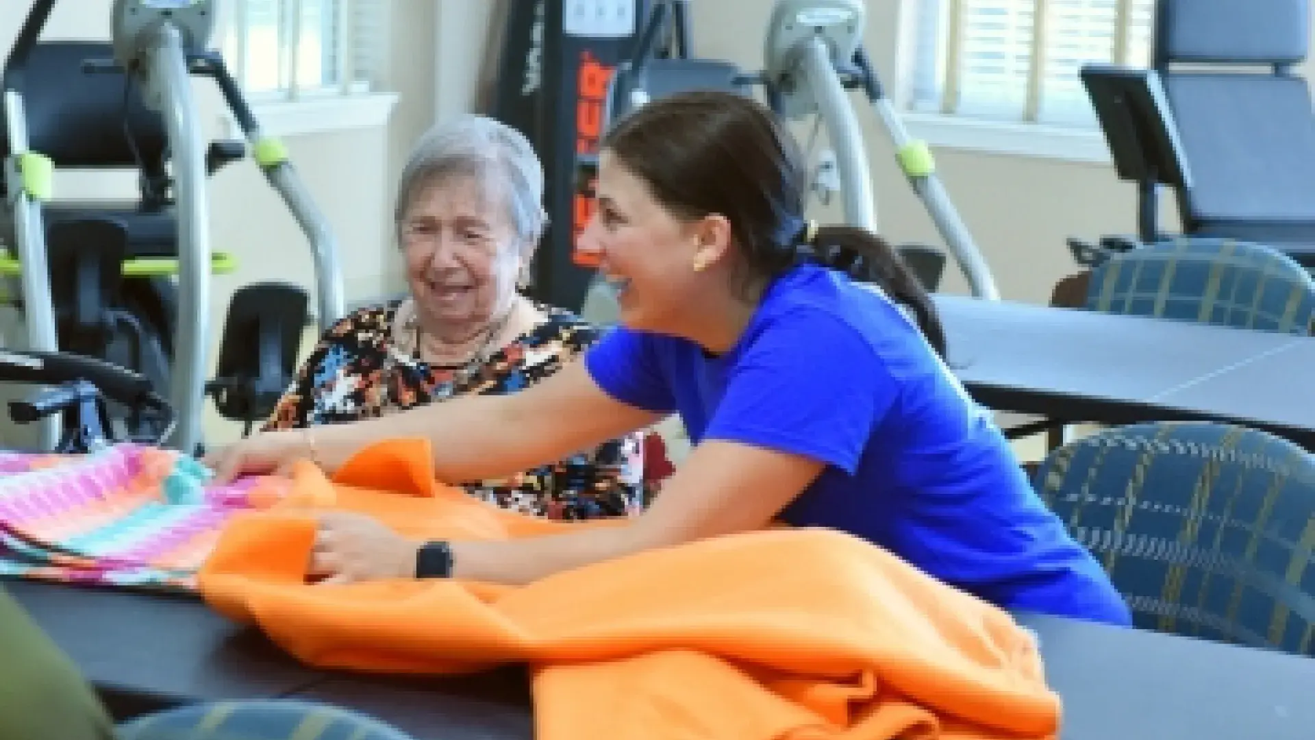 Two women laugh while working on a blanket