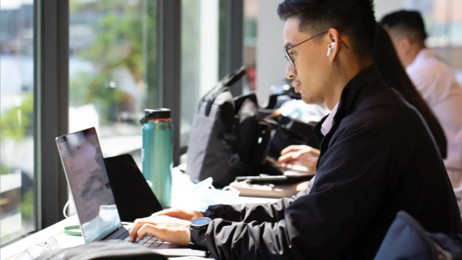 A man on a laptop working in front of a window
