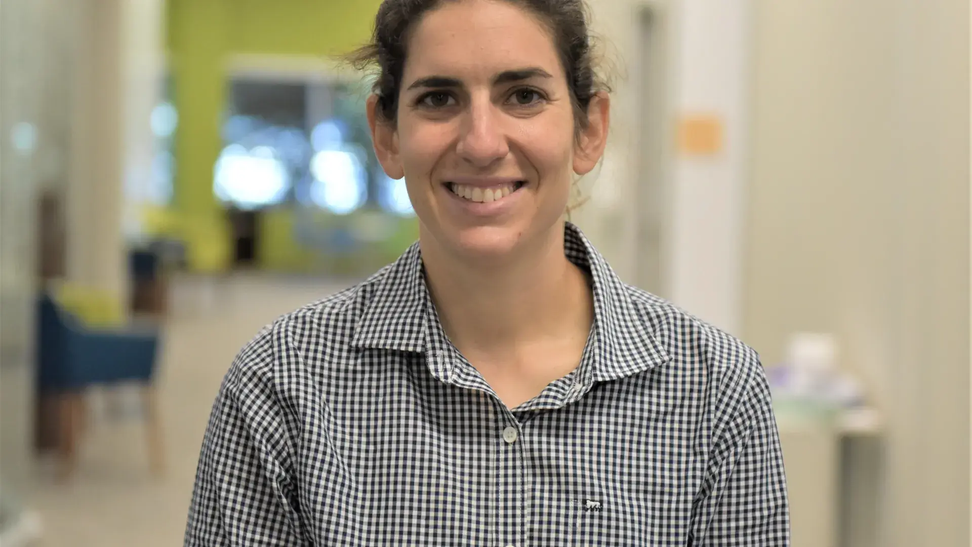 Ariel smiles for the camera in a long cream colored hallway