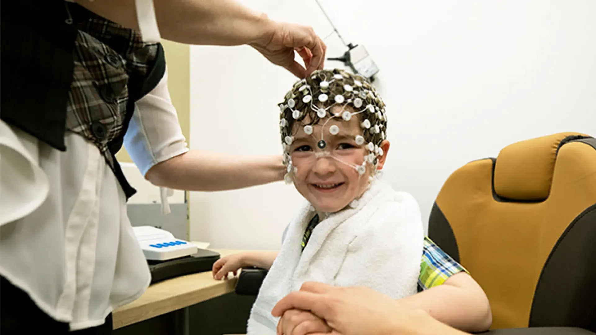 Researcher places round sensors on the head and face of a child