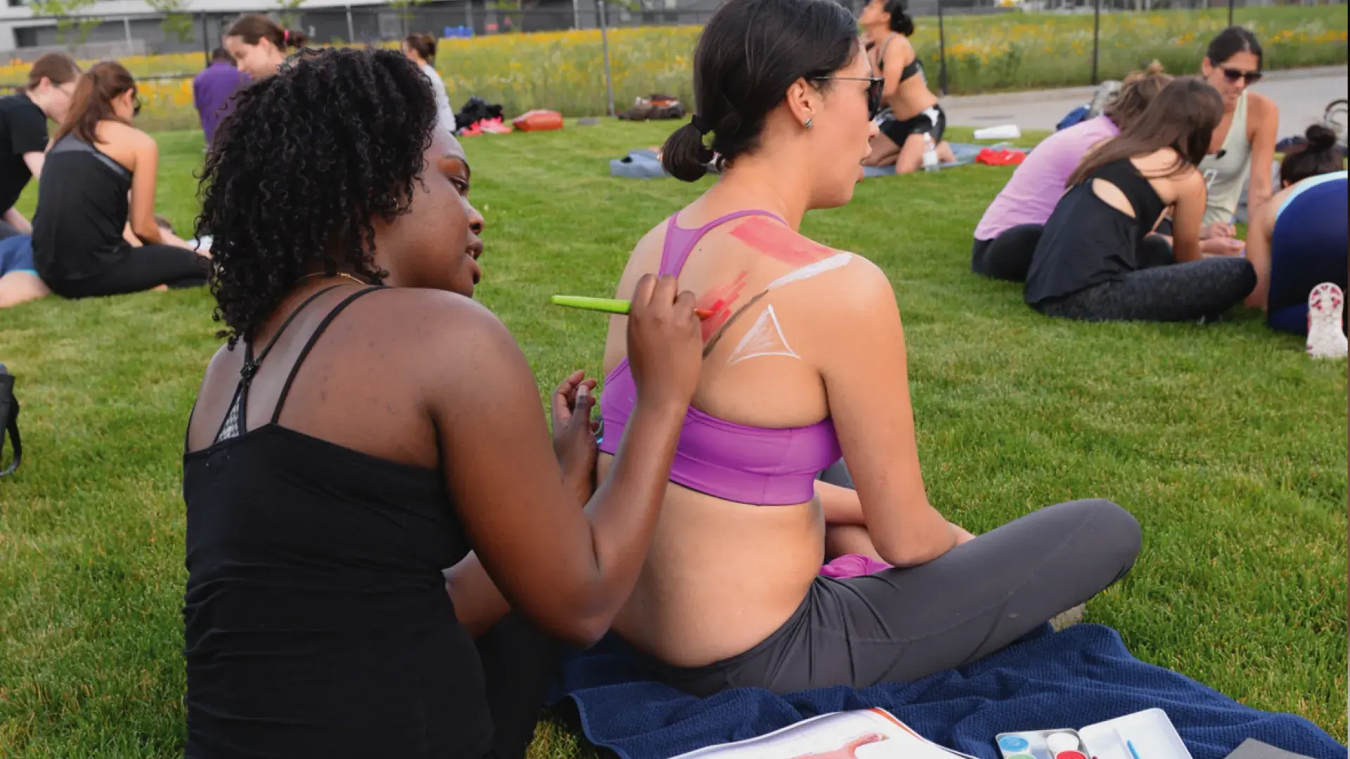 A field of people in small groups making body art on eachother