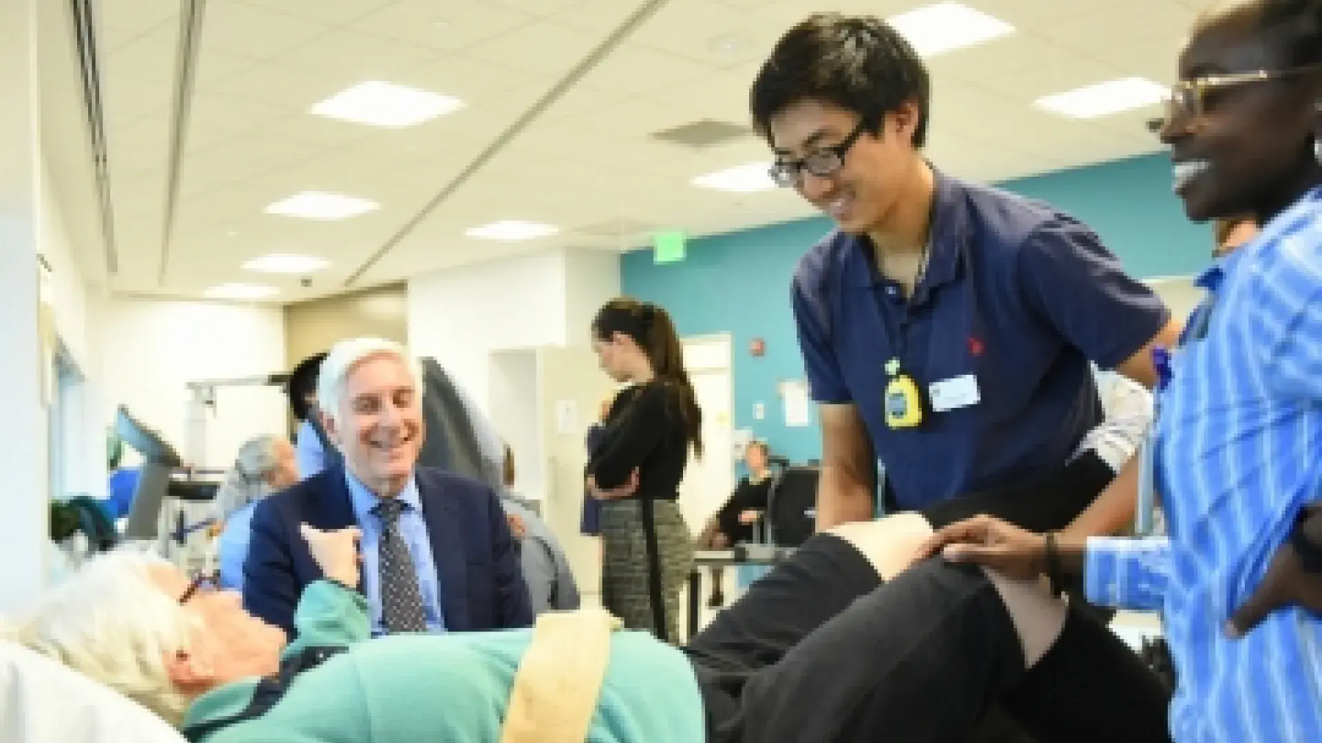 Dr. Jon LaPook of CBS News shares a laugh with Ellen O’Keefe as she receives physical therapy care from DPT students Vinson Chen and Kamaria Washington.