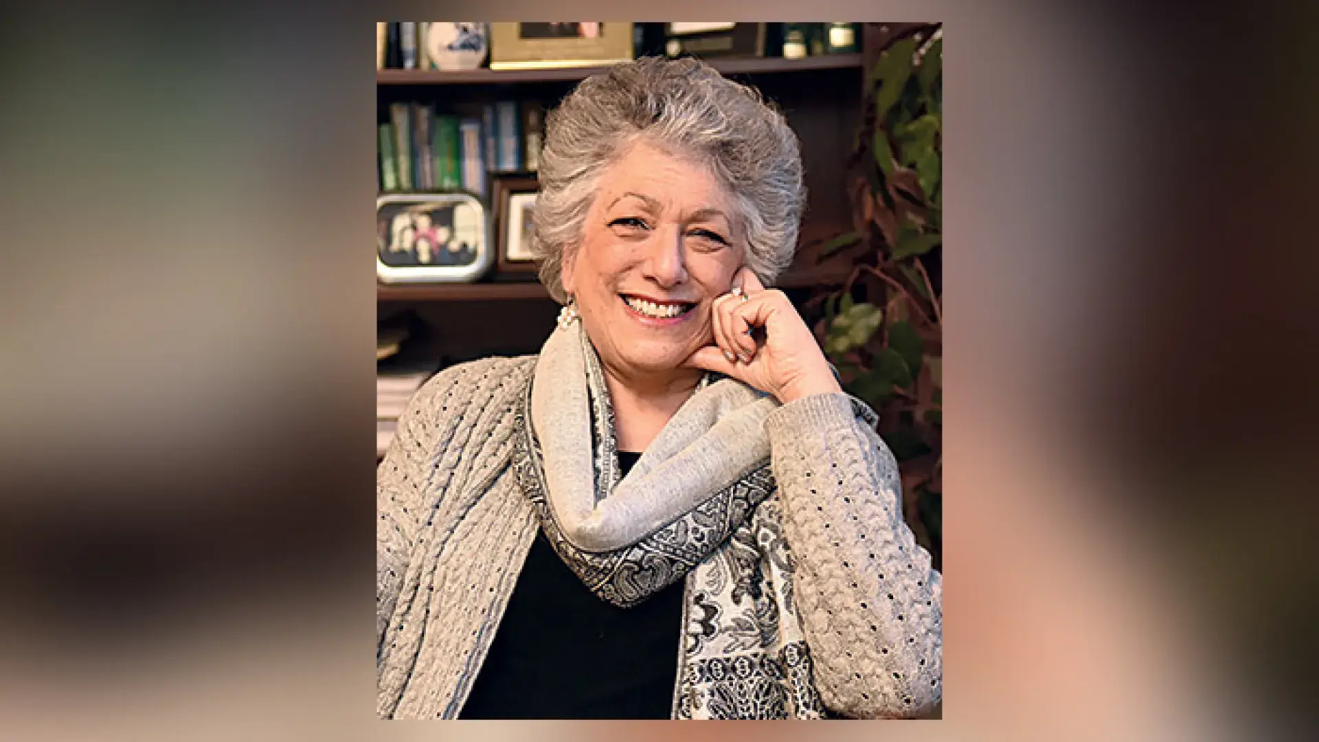 leslie smiles for the camera with her hand resting on her cheek