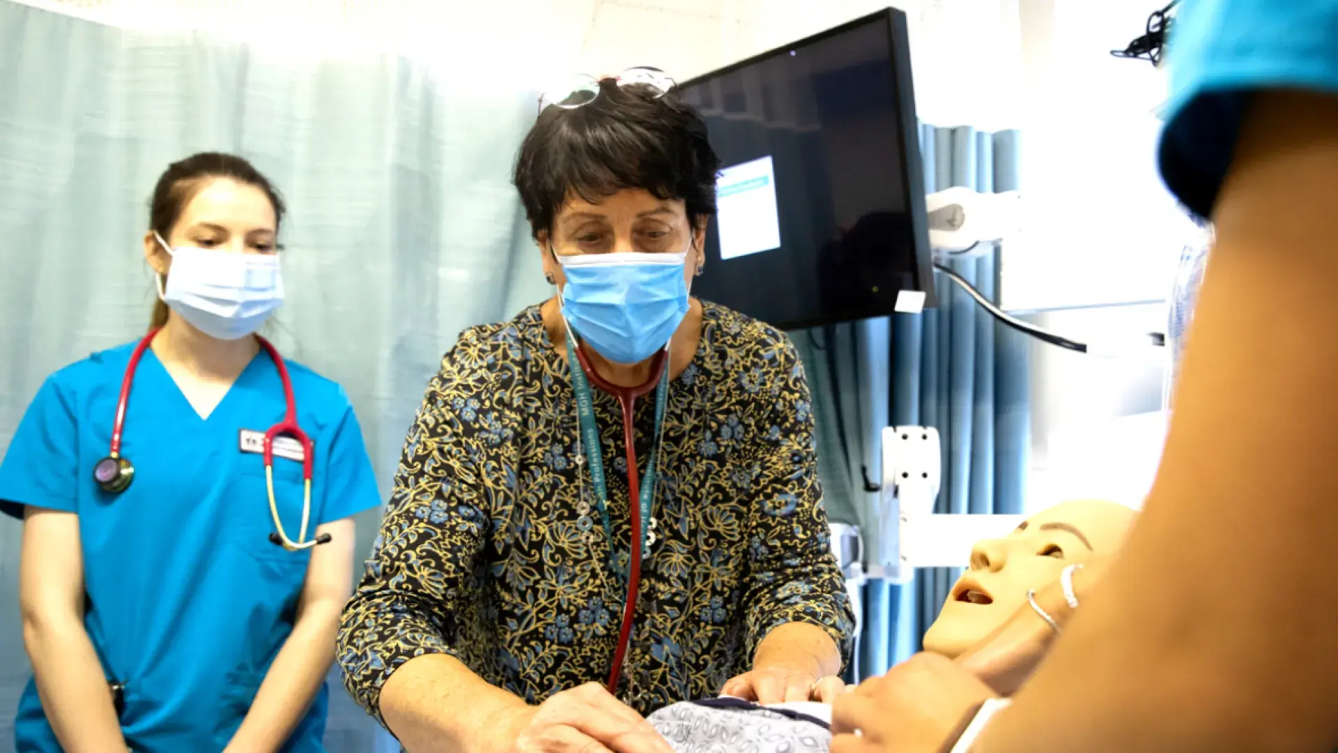 Three medical professionals working around a training dummy