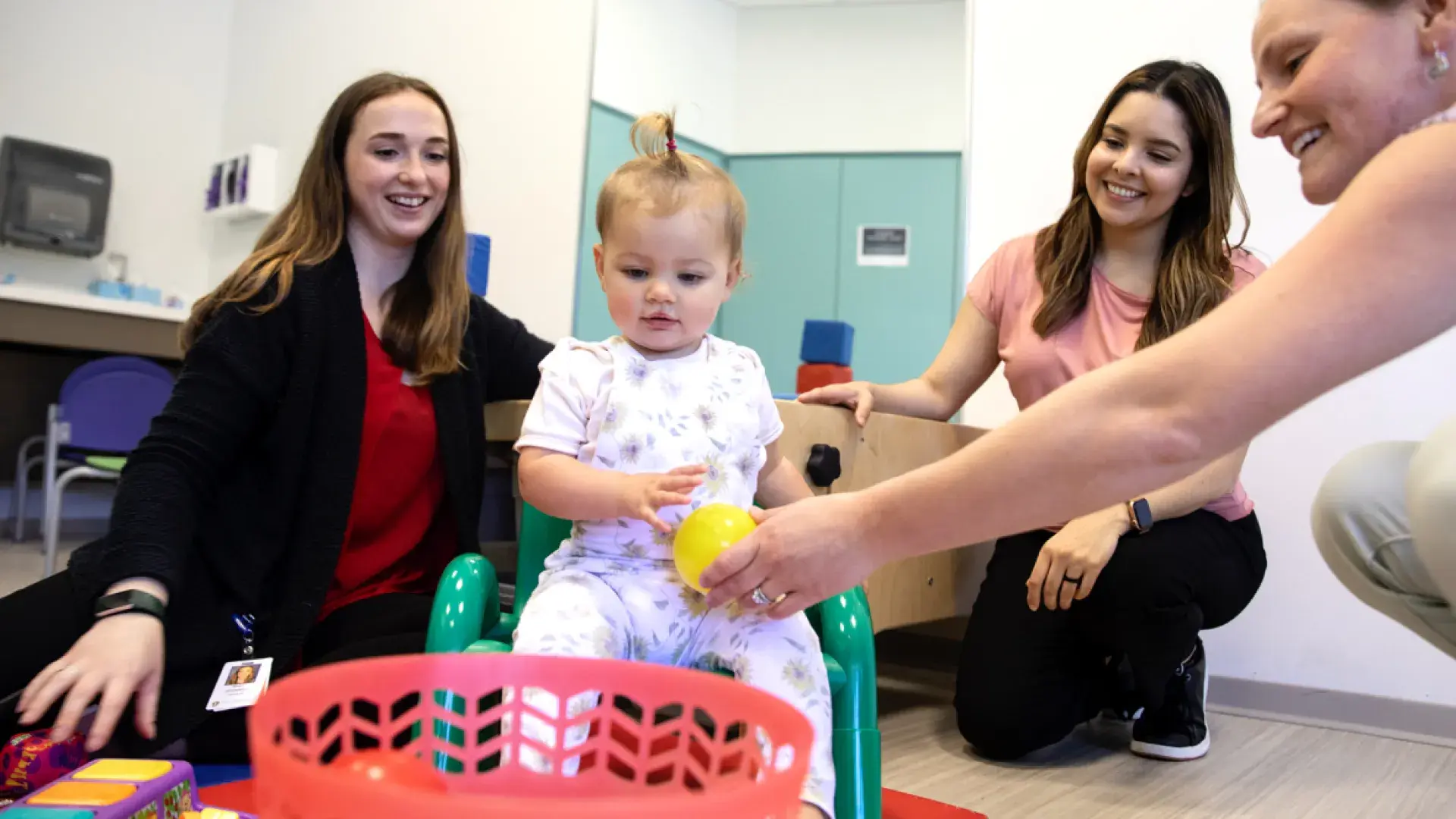 Several women playing games with a toddler 