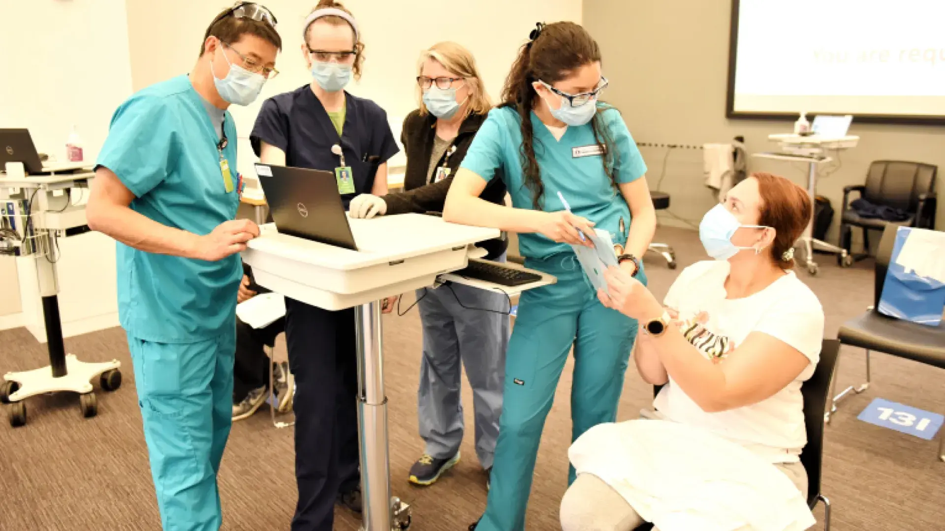 School of Nursing Instructor Patricia Pierce, center, works with BSN student Ming-Tai Kuo (far left) and RN Topaz Craig while BSN student Danielle Espinosa speaks with a patient at the MGB COVID-19 Vaccination Center.