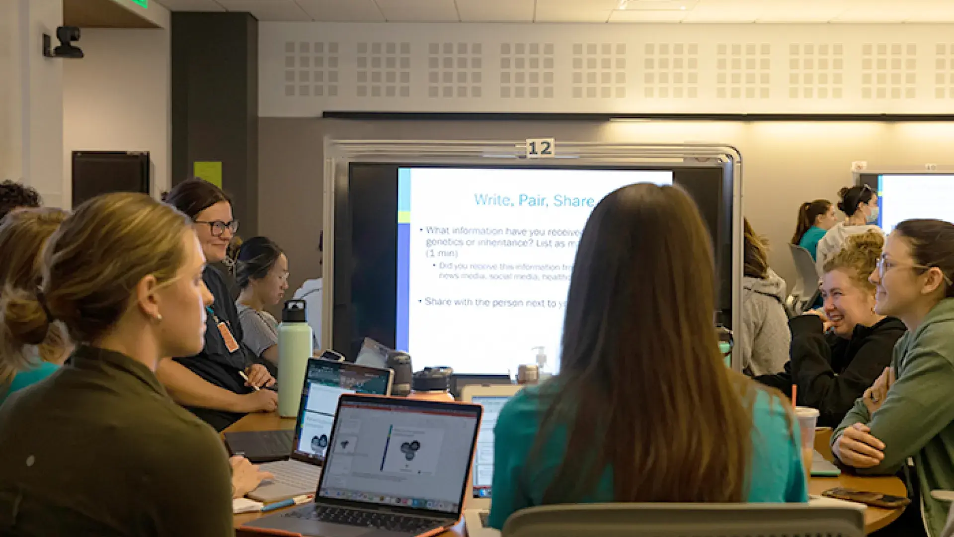 students sit around a big computer monitor