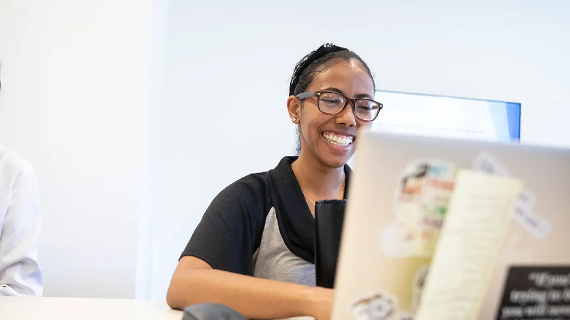 woman smiles and looks at her laptop which is covered with stickers