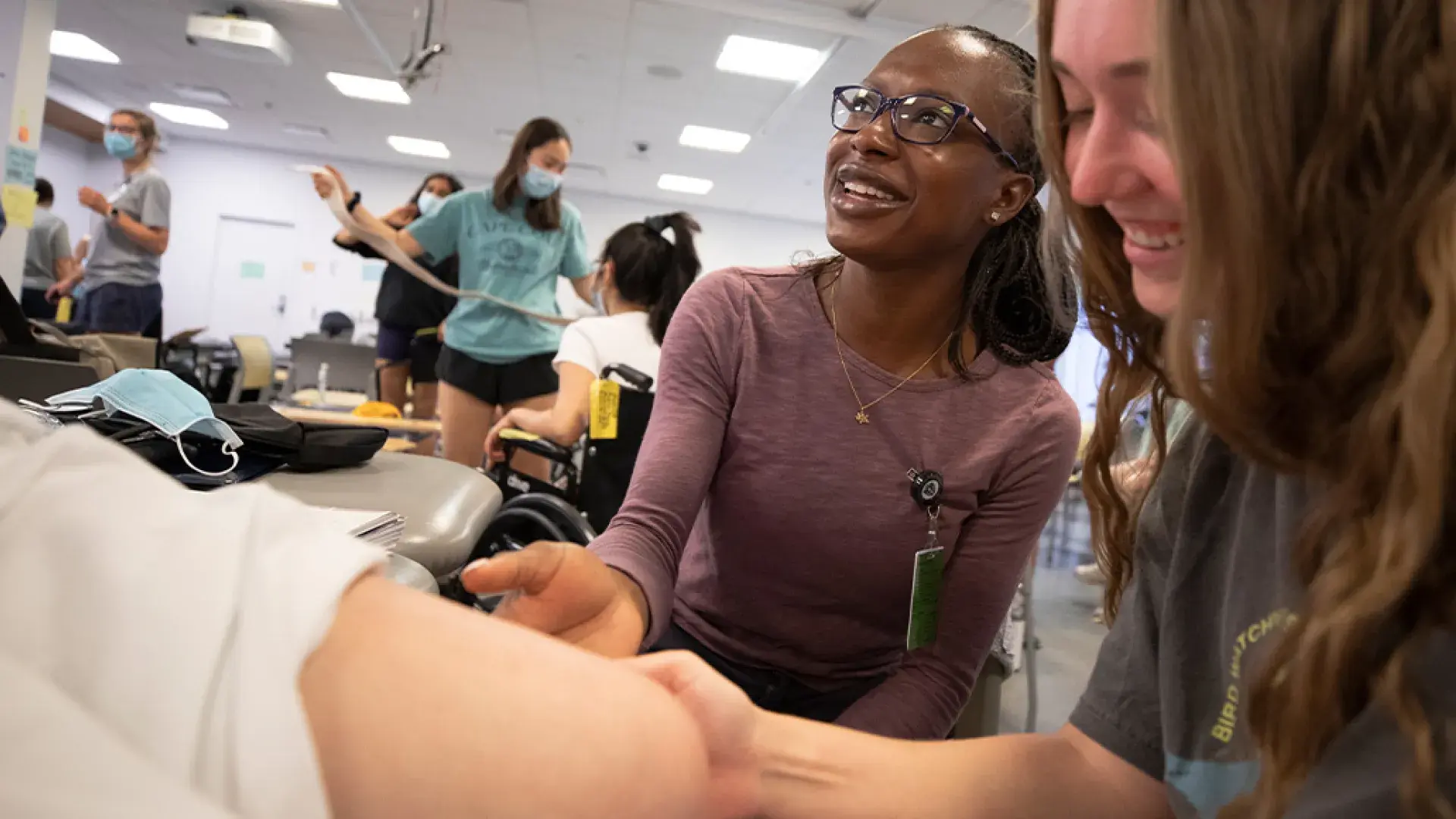 shot of classroom where students touch a patient knee together