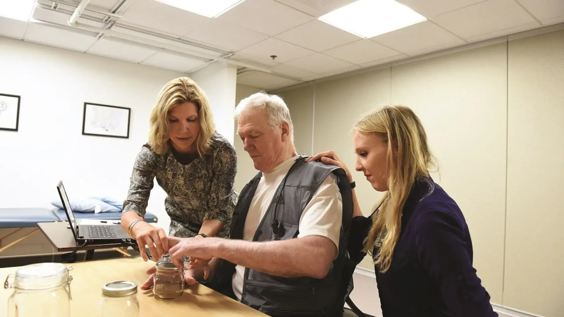 woman helps man put items into a glass ball jar on the table