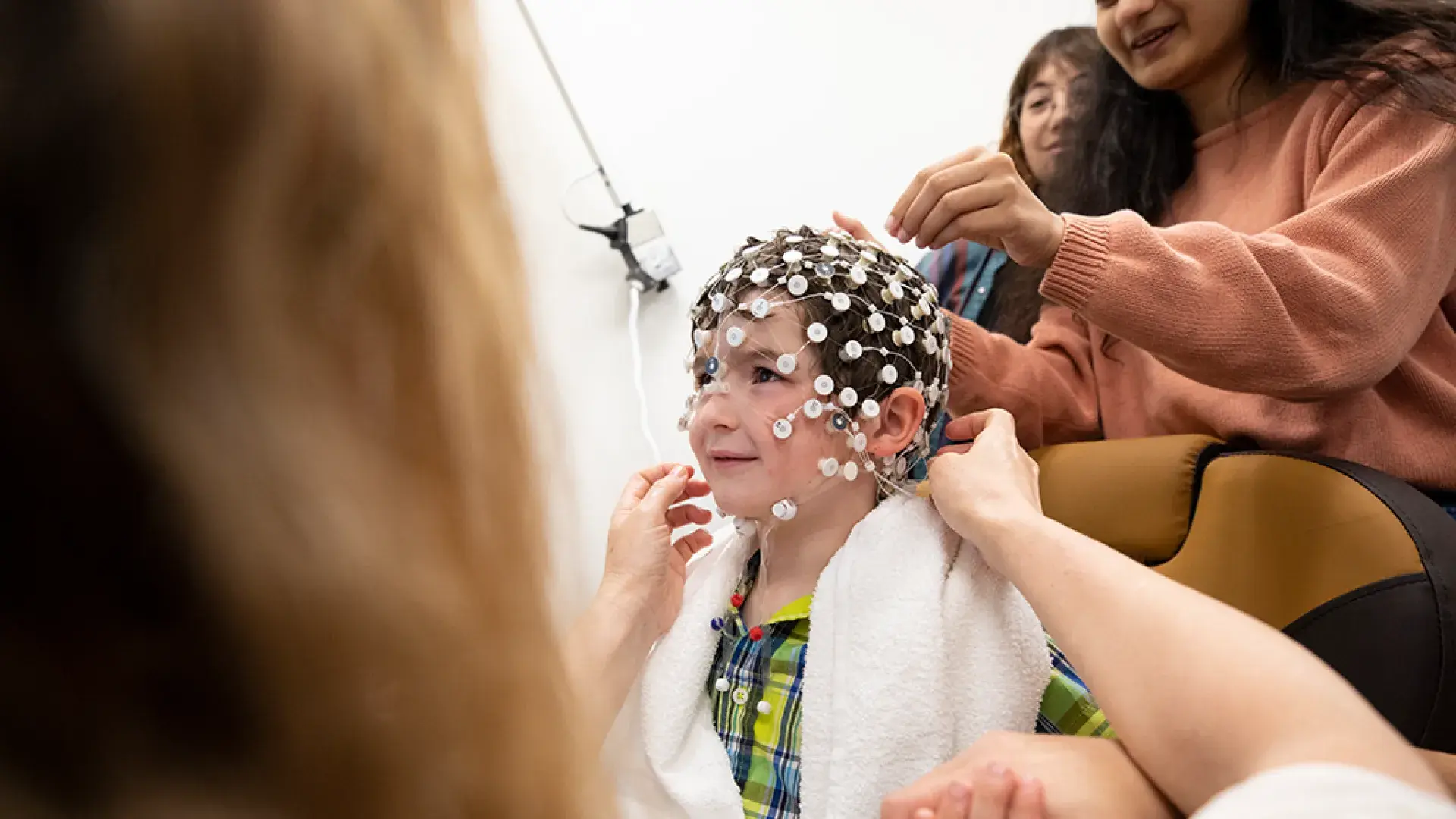 researcher places little white round sensor circles on head of a boy