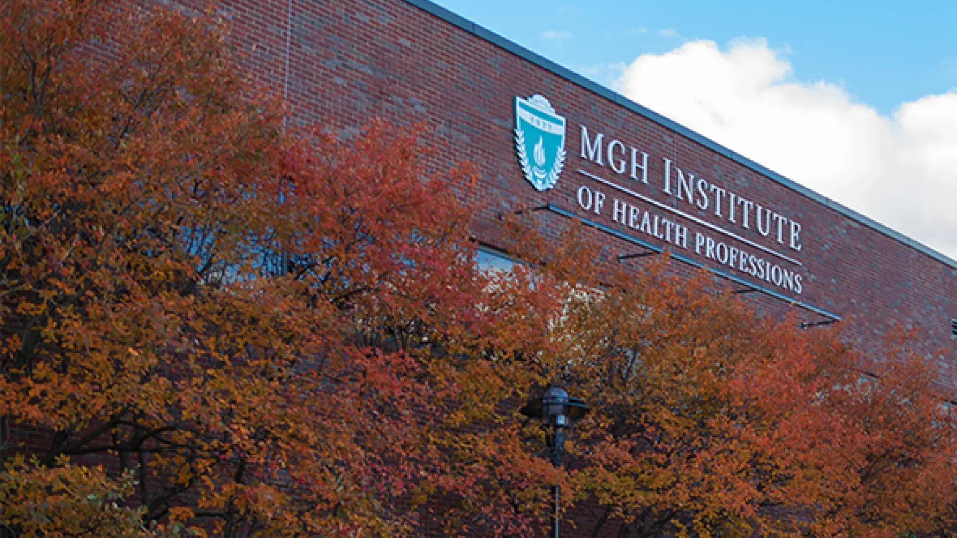 Orange and Red foliage on trees in front of brick building with IHP sign