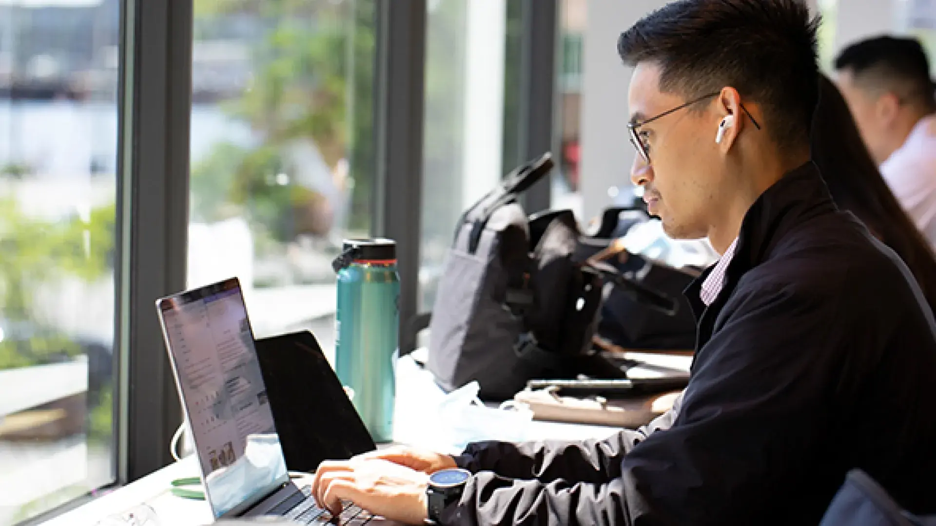Male student at laptop in front of a window