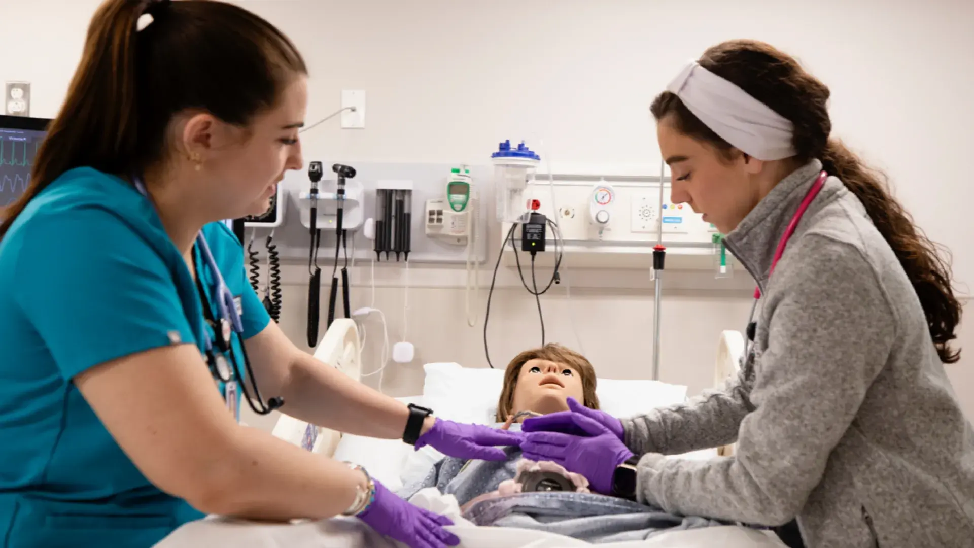 Two nurses practicing on a training manikin