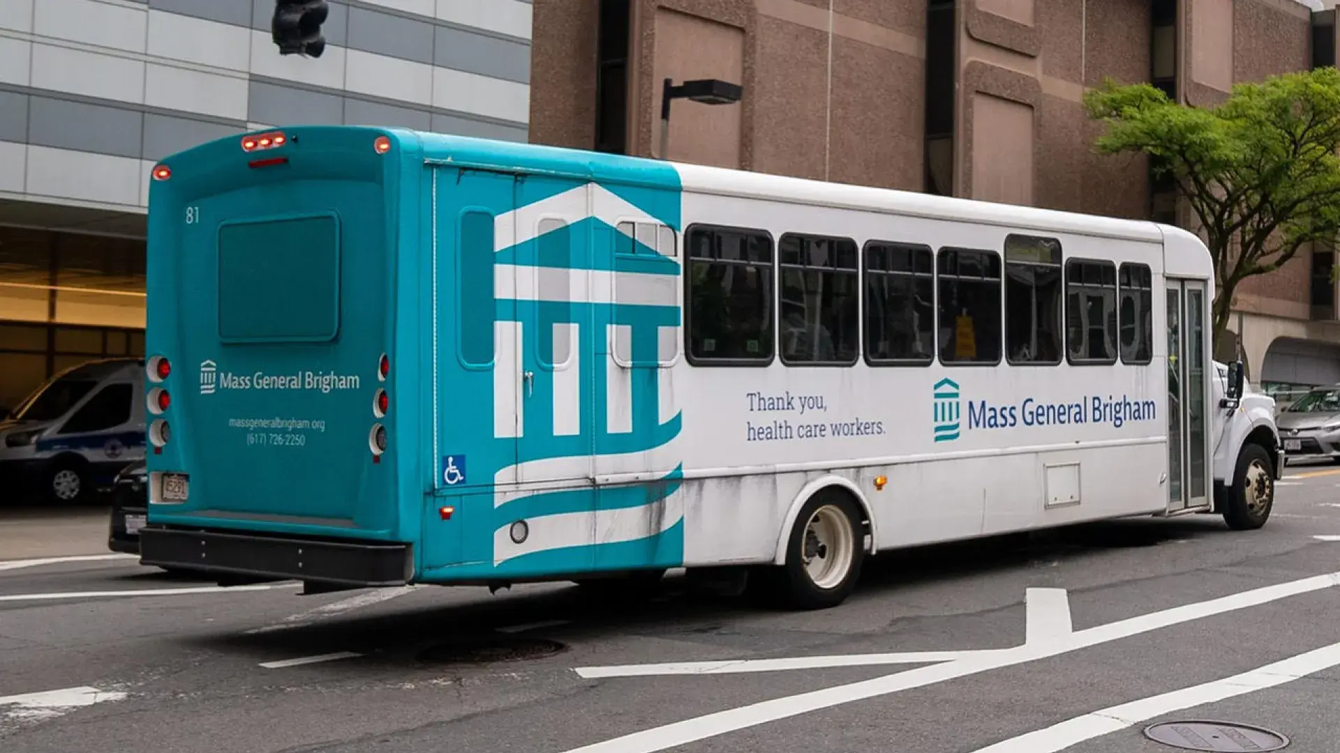 a teal and white bus drives on the road