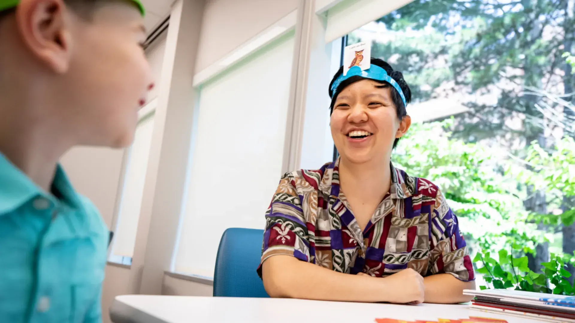 A medical professional and a child playing a card game wearing head bands