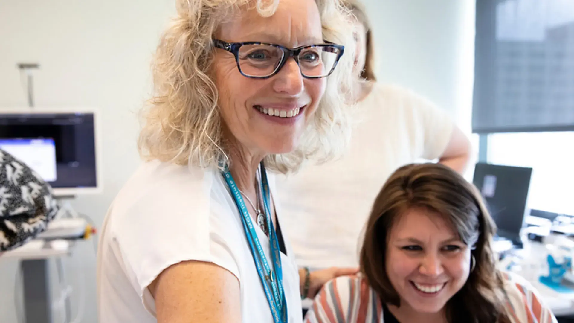 Two women smiling while focusing on something that is out of sight