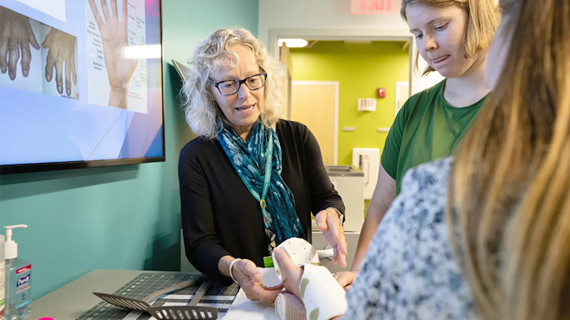 woman holds another woman's hand in a splint while another looks on