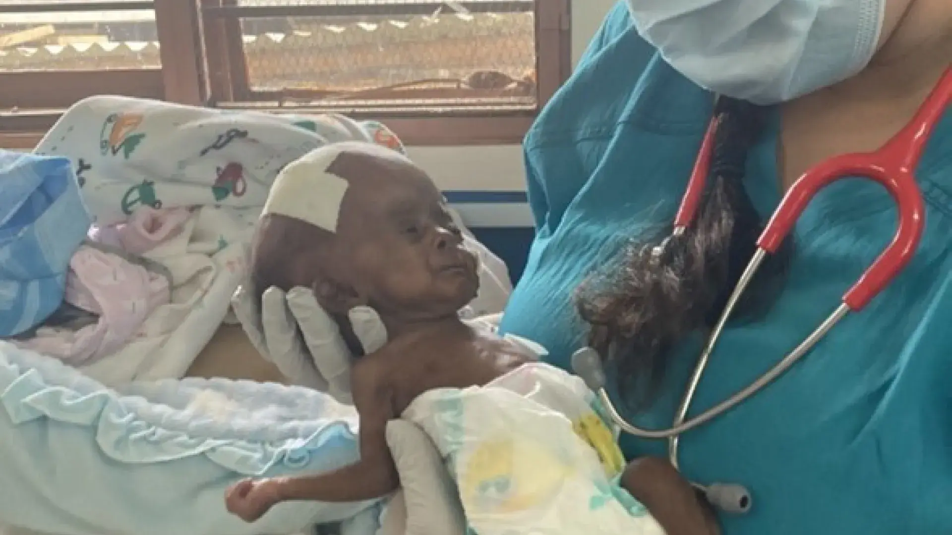 woman in mask holds tiny Black baby