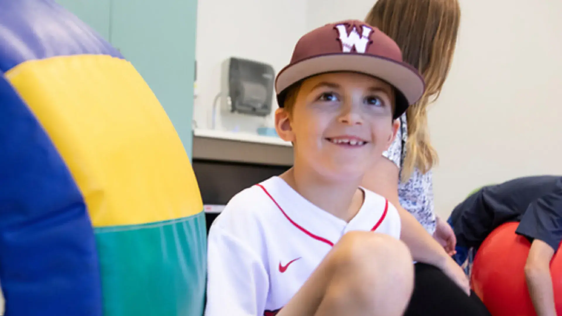 A young boy smiling while wearing a baseball hat