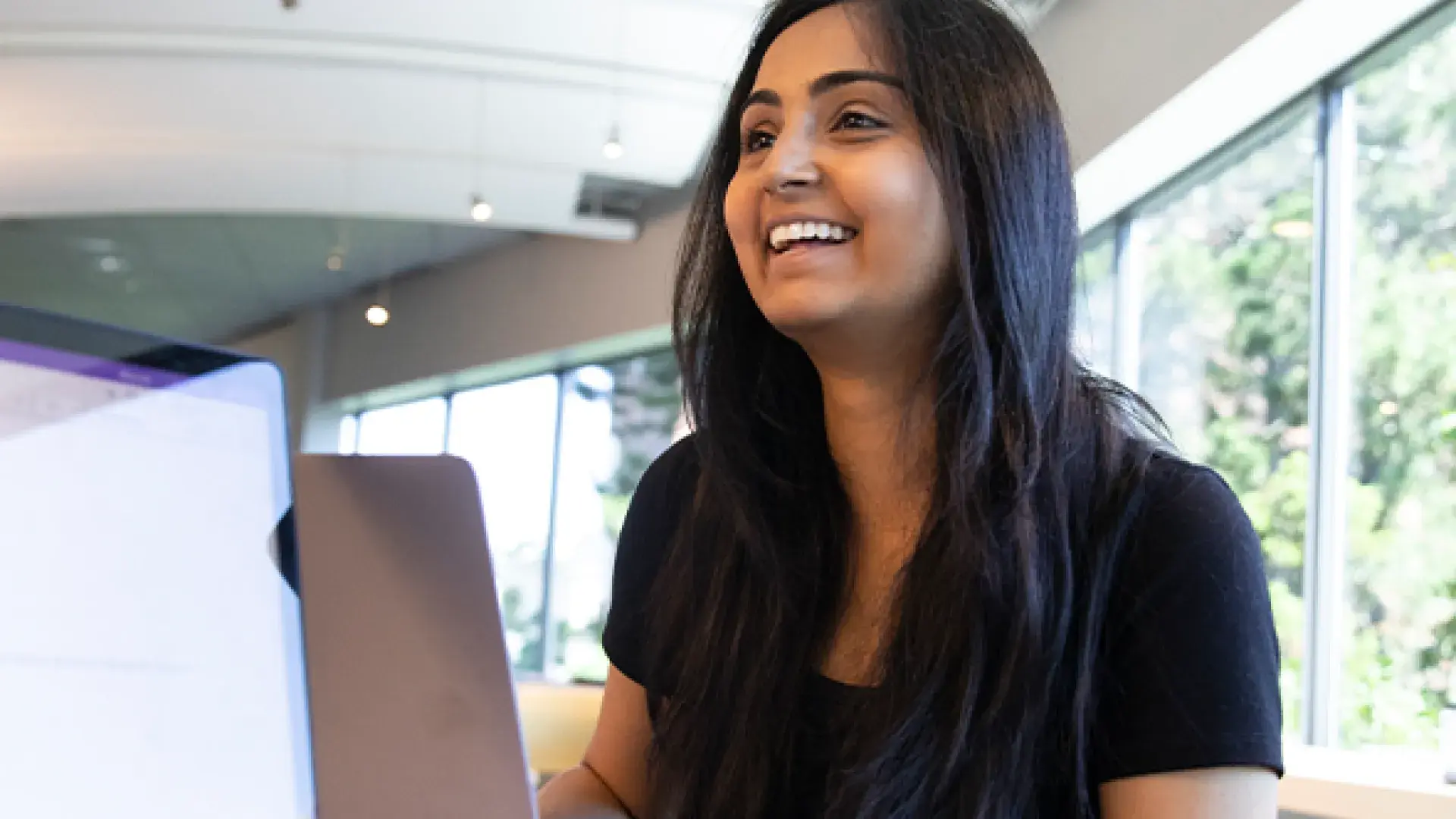 Woman smiles over laptop in study group