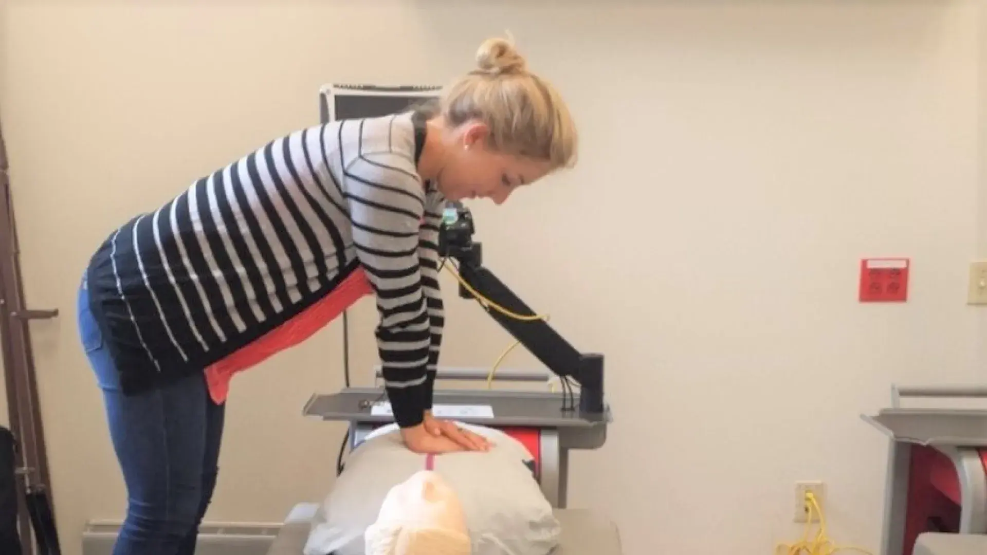 woman performs chest compressions on a manikin